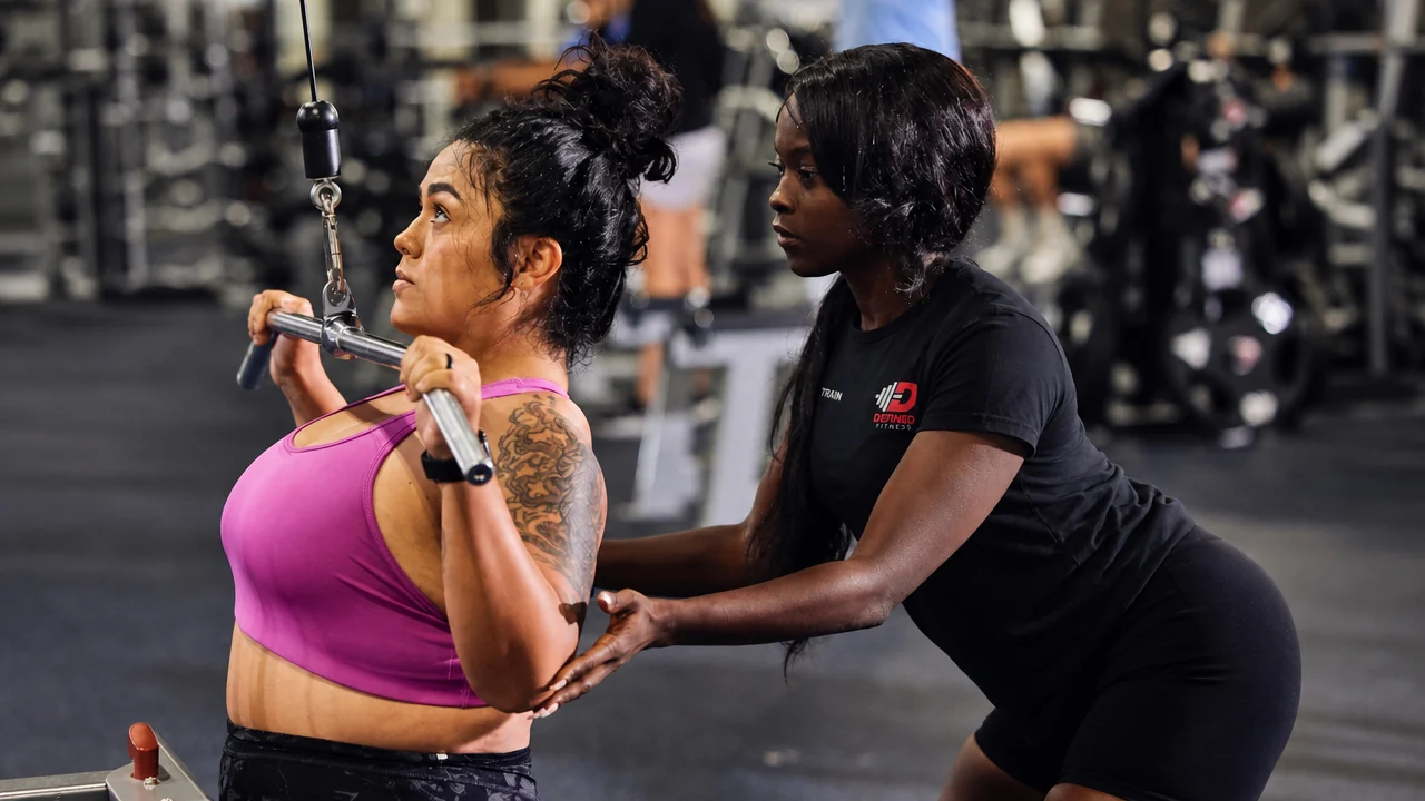A trainer coaching a member through a lat pulldown